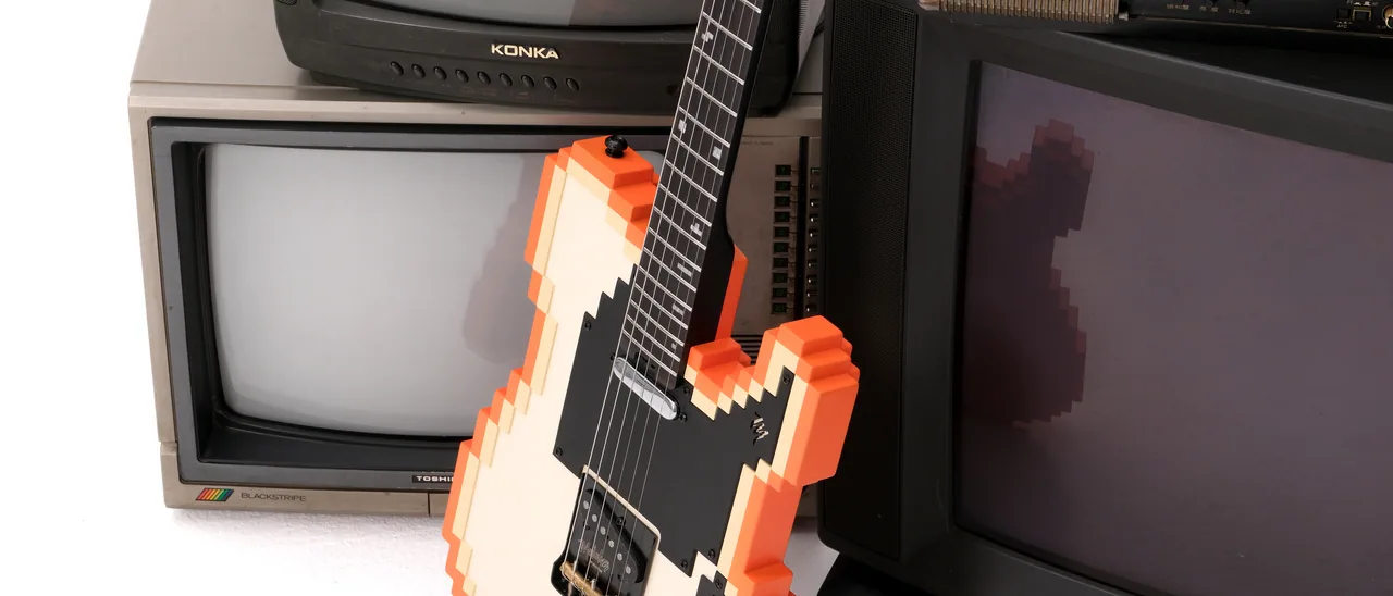 ブラウン管テレビの山に立てかけたSTAGE-T（OR）。ボディからネックへ斜めに伸びる線